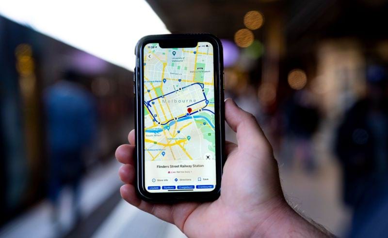 Hand holding mobile phone showing a map of public transport