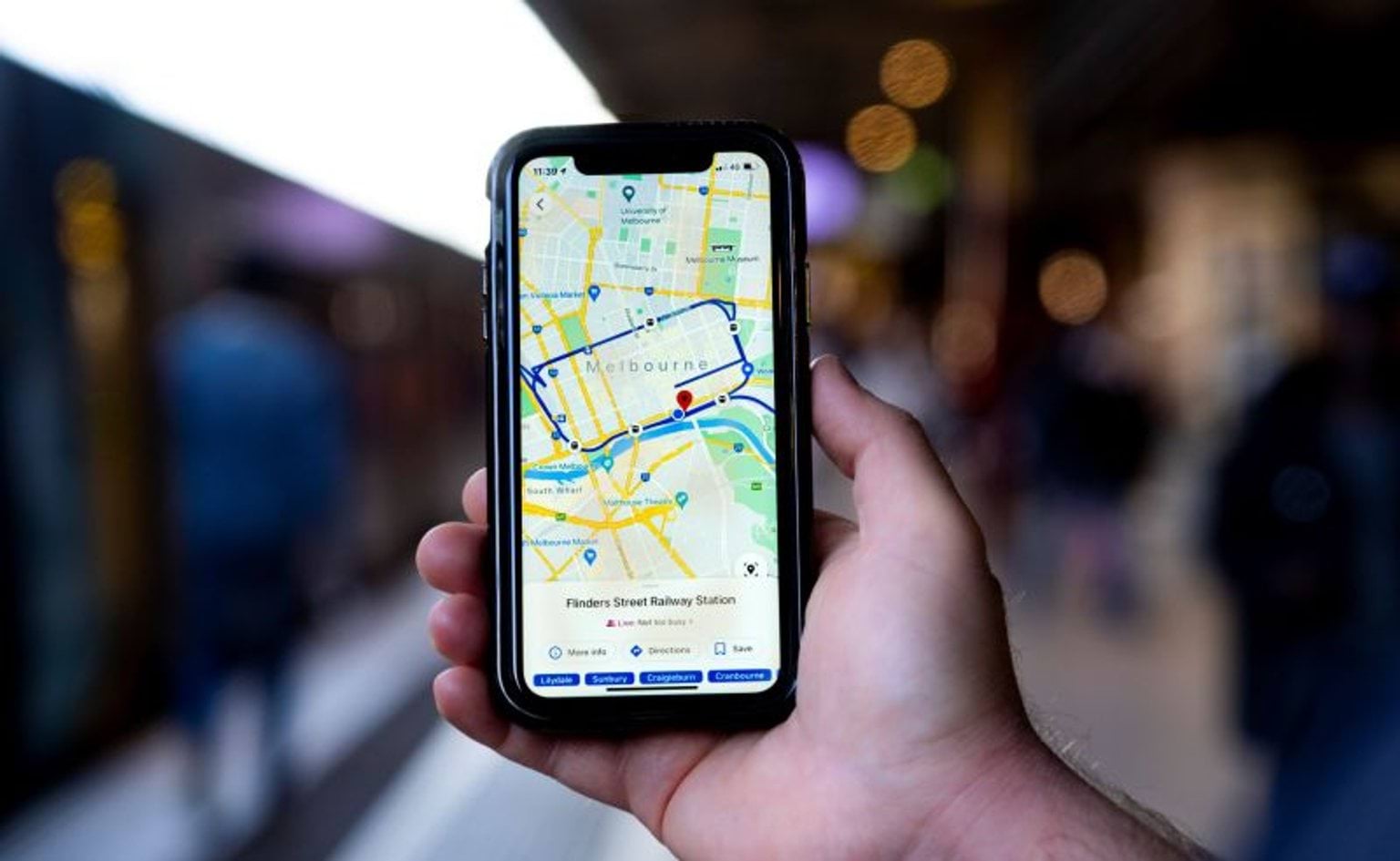 Hand holding mobile phone showing a map of public transport